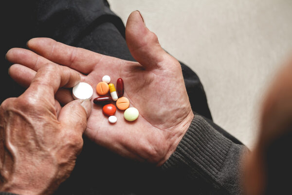 A hand with multiple pills of different colors and shapes