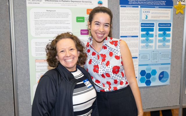 Lauren Brookman-Frazee and Laurel Benjamin pose in front of poster.