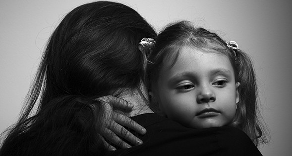 Family lifestyle. Daughter hugging her mother and looking serious. Black and white portrait