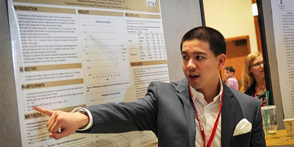 Moreno pointing something out on his poster at Student Research Symposium