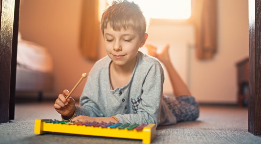 child on bedroom floor playing xylophone 