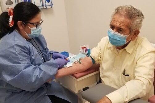 A man wearing a mask gets his blood drawn at the South Bay Latino Research Center