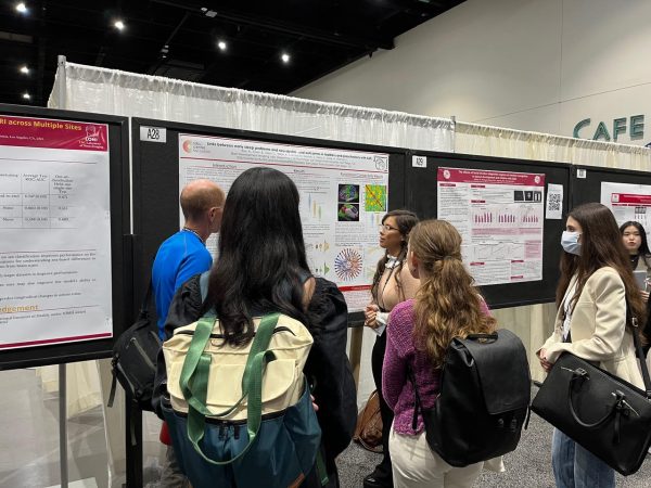 Adriana Rios discusses her poster with a group of conference attendees