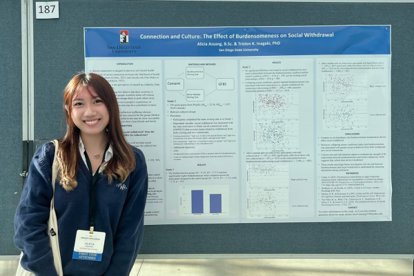 Student standing next to her research presentation poster at a conference