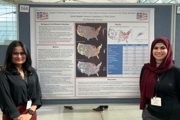 Two female students standing next to their research presentation poster at a conference