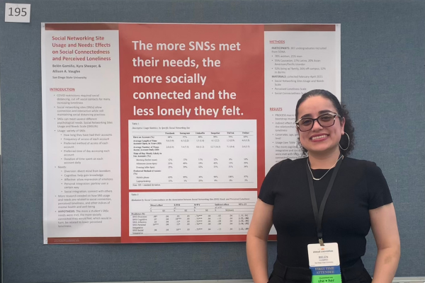 Student standing next to her research presentation poster at a conference