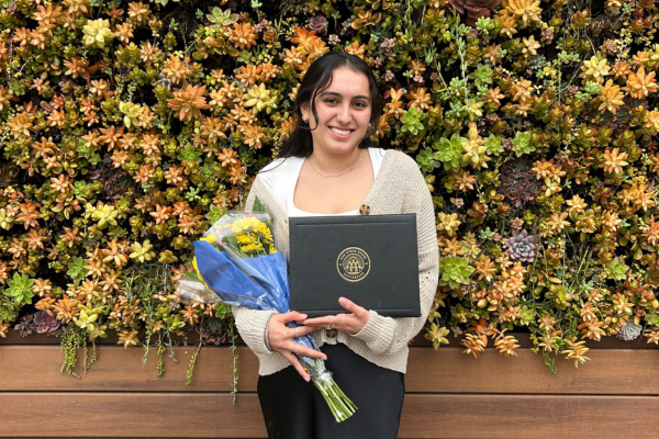 Student standing outside holding her research award