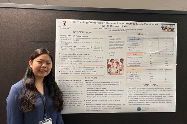 Student standing next to her research presentation poster at a conference