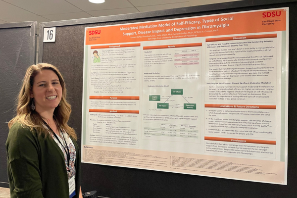 Female student standing next to her research presentation poster at a conference