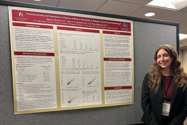 Student standing next to her research presentation poster at a conference