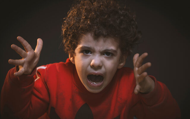 Closeup of angy boy with hands reaching at you and yelling.