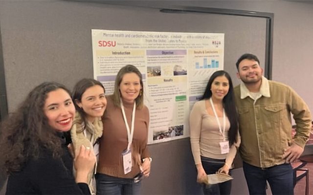 4 students standing in front fo a research poster with professor Jessica McCurley.