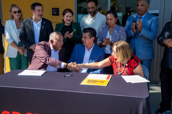 a Seated President de la Torre shaking hands with SWC officals outisde at table.
